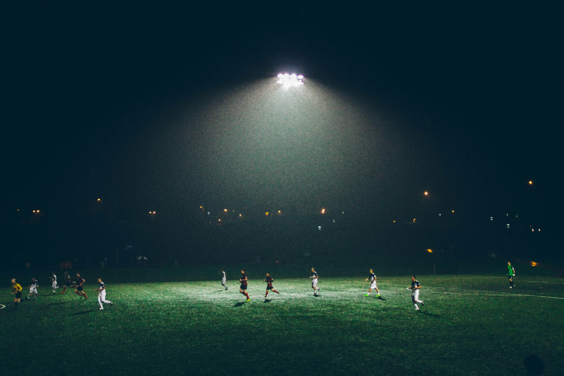 Football players training under floodlights at night — illustration of sports technology and performance comparison on Skuadx.